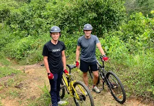 Two guests with mountain bikes on a jungle trail